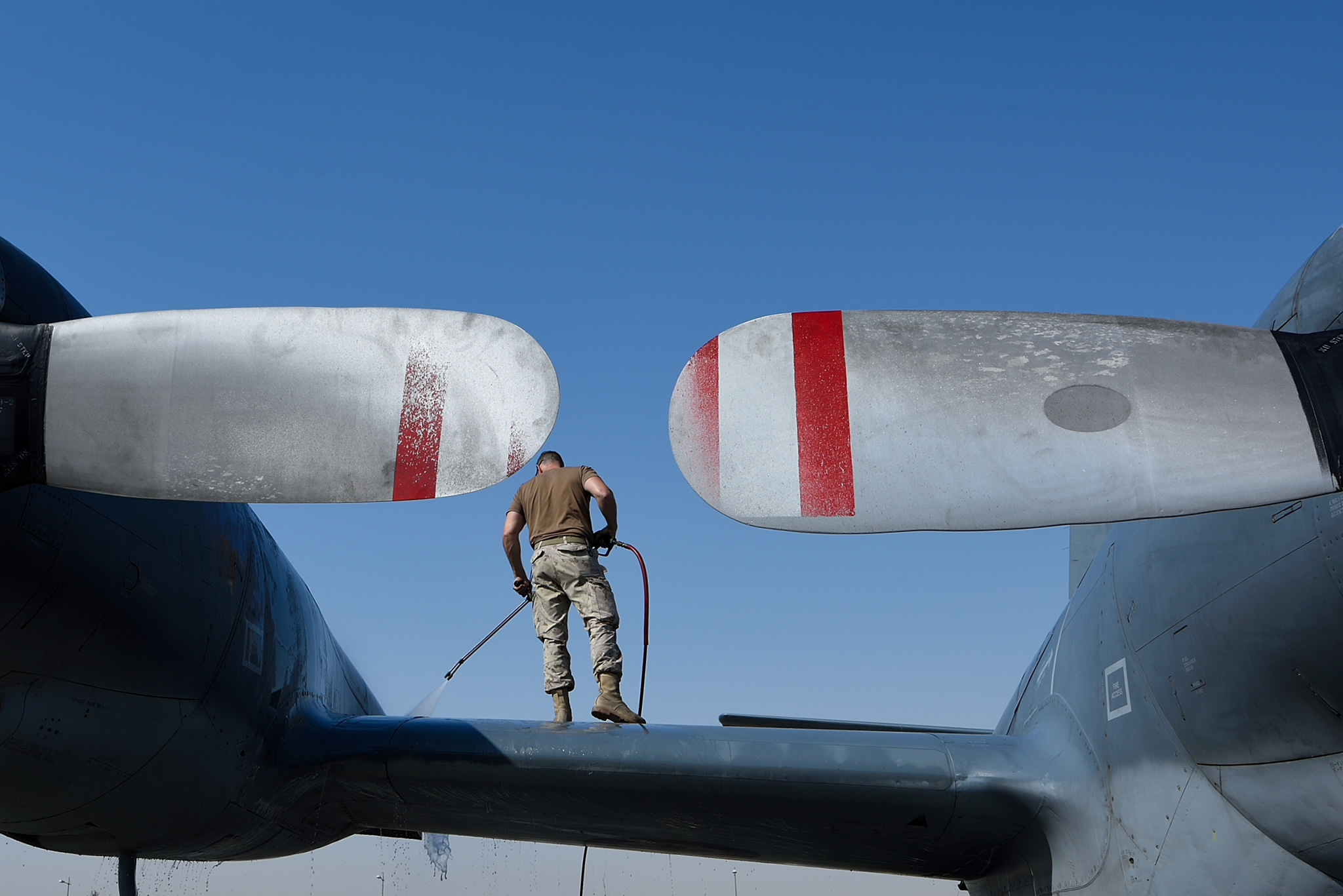 To keep the aircraft functioning properly in a desert environment, an aviation technician sprays down the wing and fuselage of a CP-140 Aurora in Kuwait during Operation IMPACT on April 4, 2016.