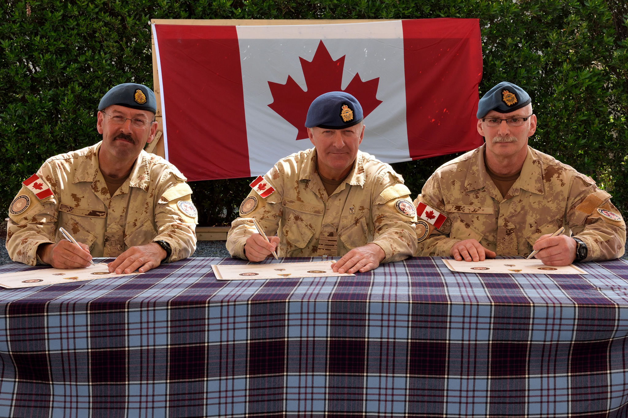 Chief Warrant Officer Bill Hinchey (left), Air Task Force – Iraq Chief Warrant Officer, hands the senior appointment to Chief Warrant Officer Luigi Di Stephano as Colonel Shayne Elder makes the change over official during a ceremony in Kuwait on April 8, 2016. Photo: Op Impact, DND